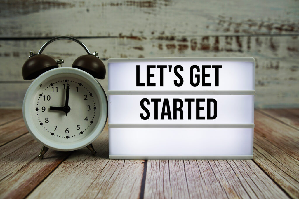 let's get started text on light box with alarm clock on wooden background
